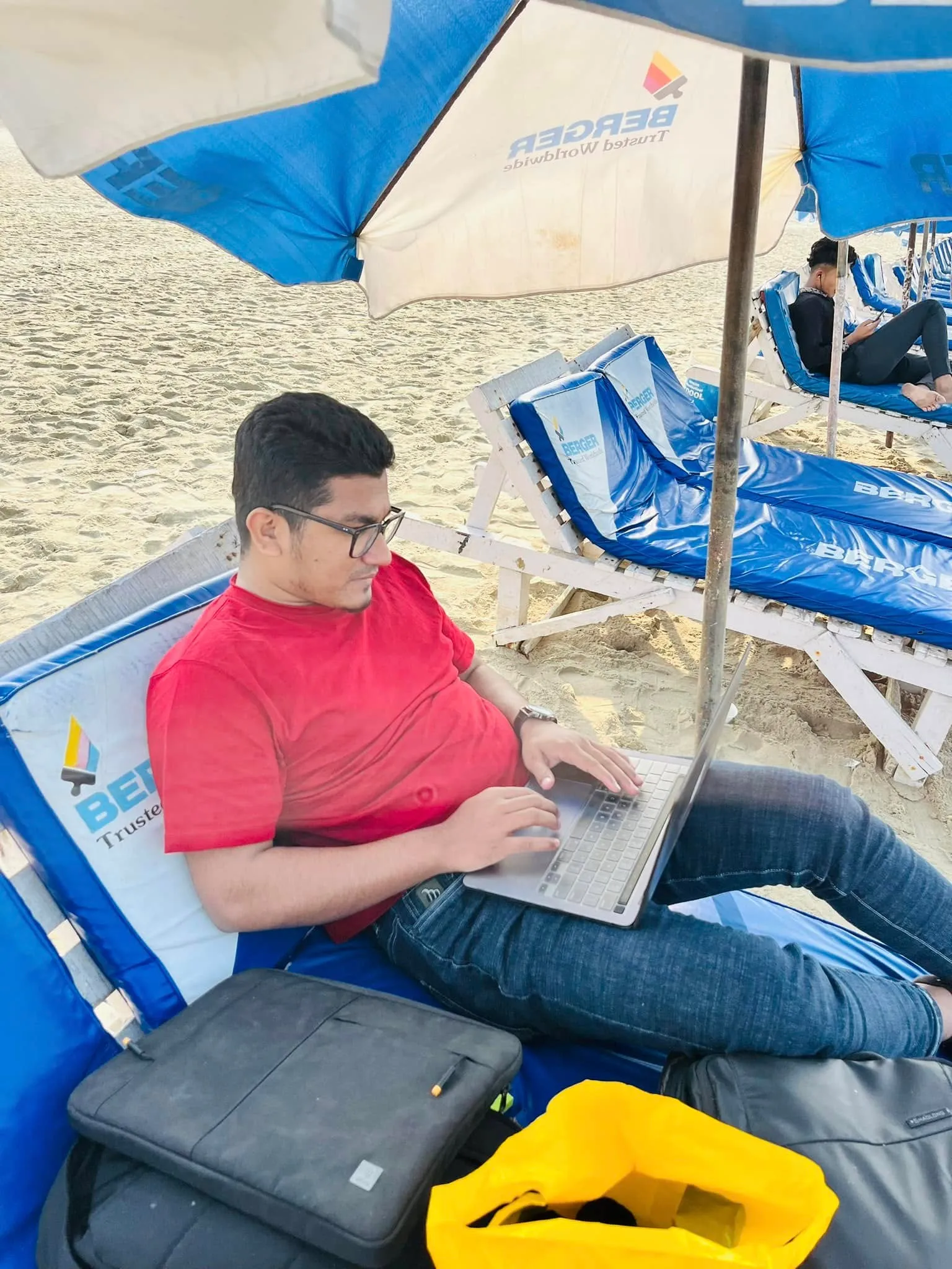 Shakawat Hridoy working on a laptop from a lounger on the beach at Cox's Bazar, Bangladesh