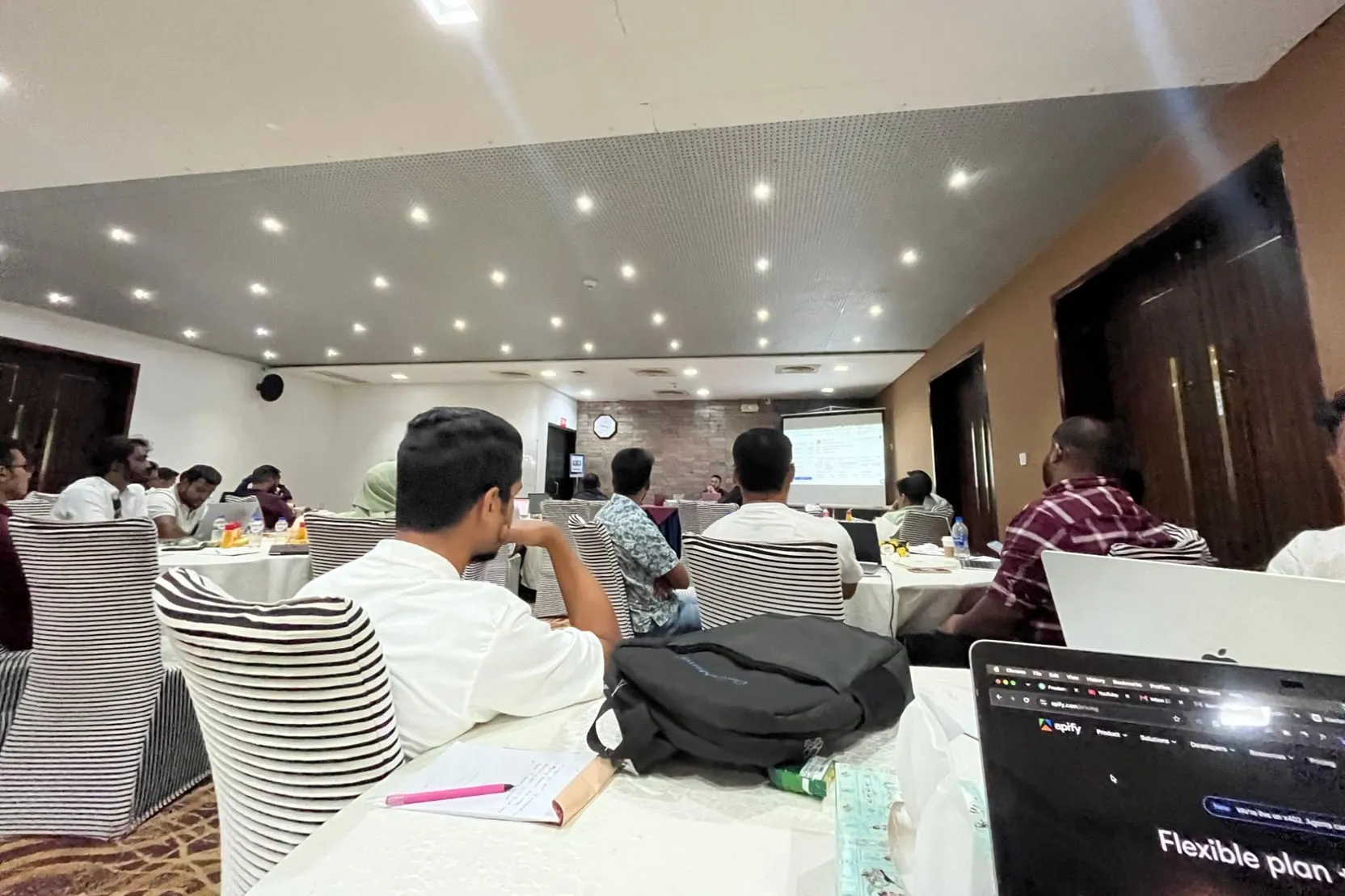 Attendees with laptops open, following a session on the projector screen at BITPA Conference 2026
