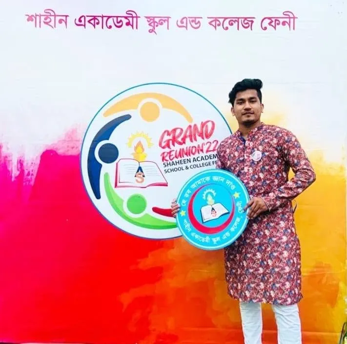Shakawat Hridoy in a patterned panjabi holding a Grand Reunion sign at Shaheen Academy School and College, Feni