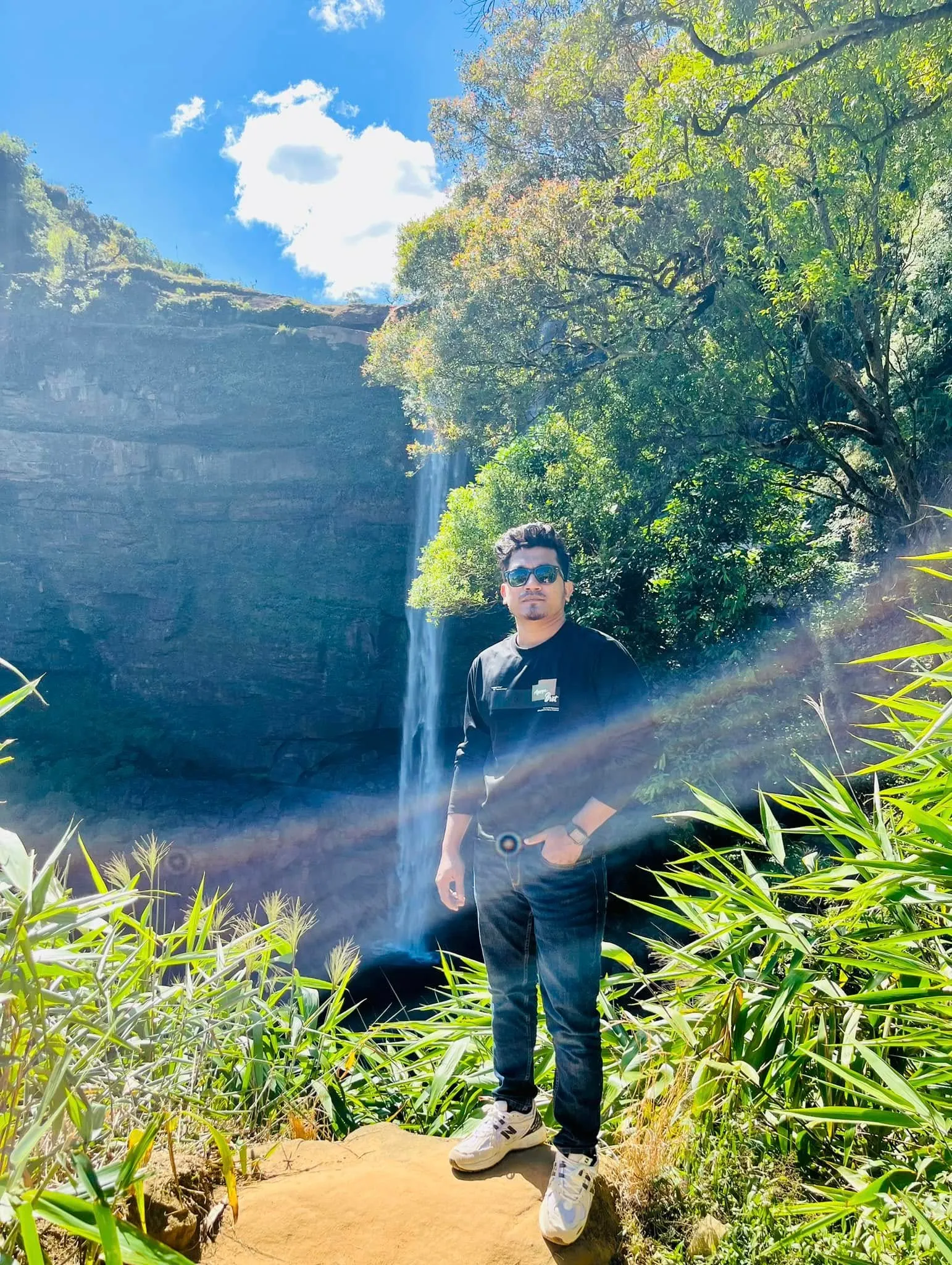 A tall waterfall dropping into a green gorge in the hills of Meghalaya, India