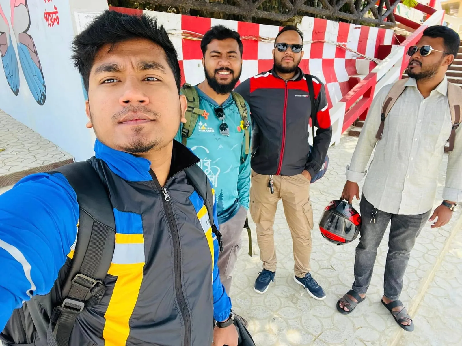 Shakawat Hridoy taking a selfie with three friends in riding jackets on a bike trip in Rangamati