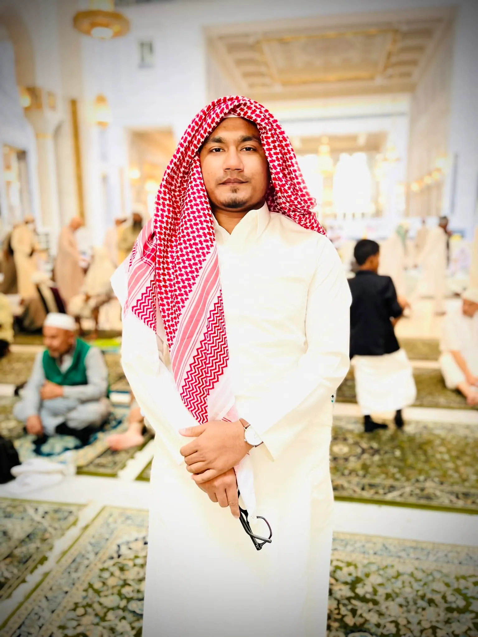 Shakawat Hridoy in a white thobe and red shemagh at a mosque courtyard in Saudi Arabia