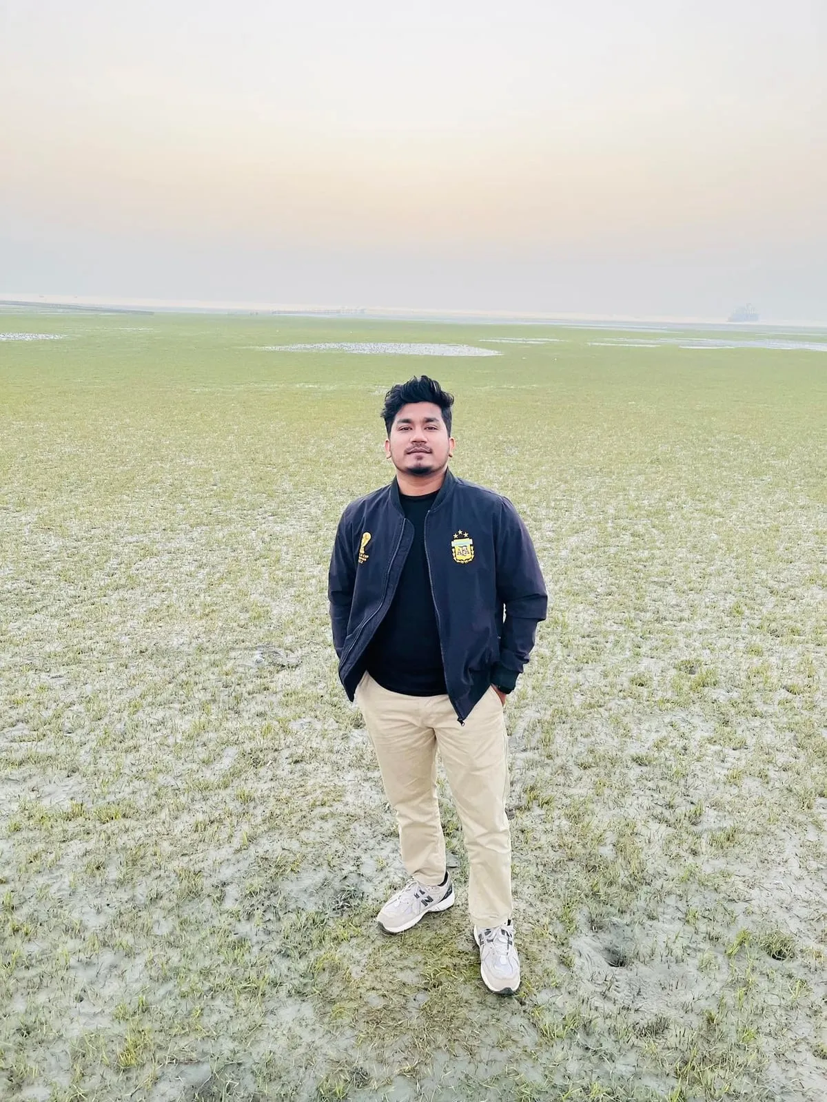 Shakawat Hridoy standing on the wide open grassland of Tanguar Haor, Sunamganj