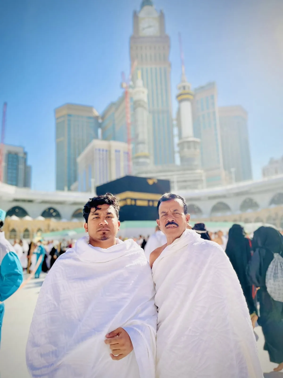 Shakawat Hridoy in ihram at the Grand Mosque in Makkah during Umrah, with the Kaaba and the clock tower behind